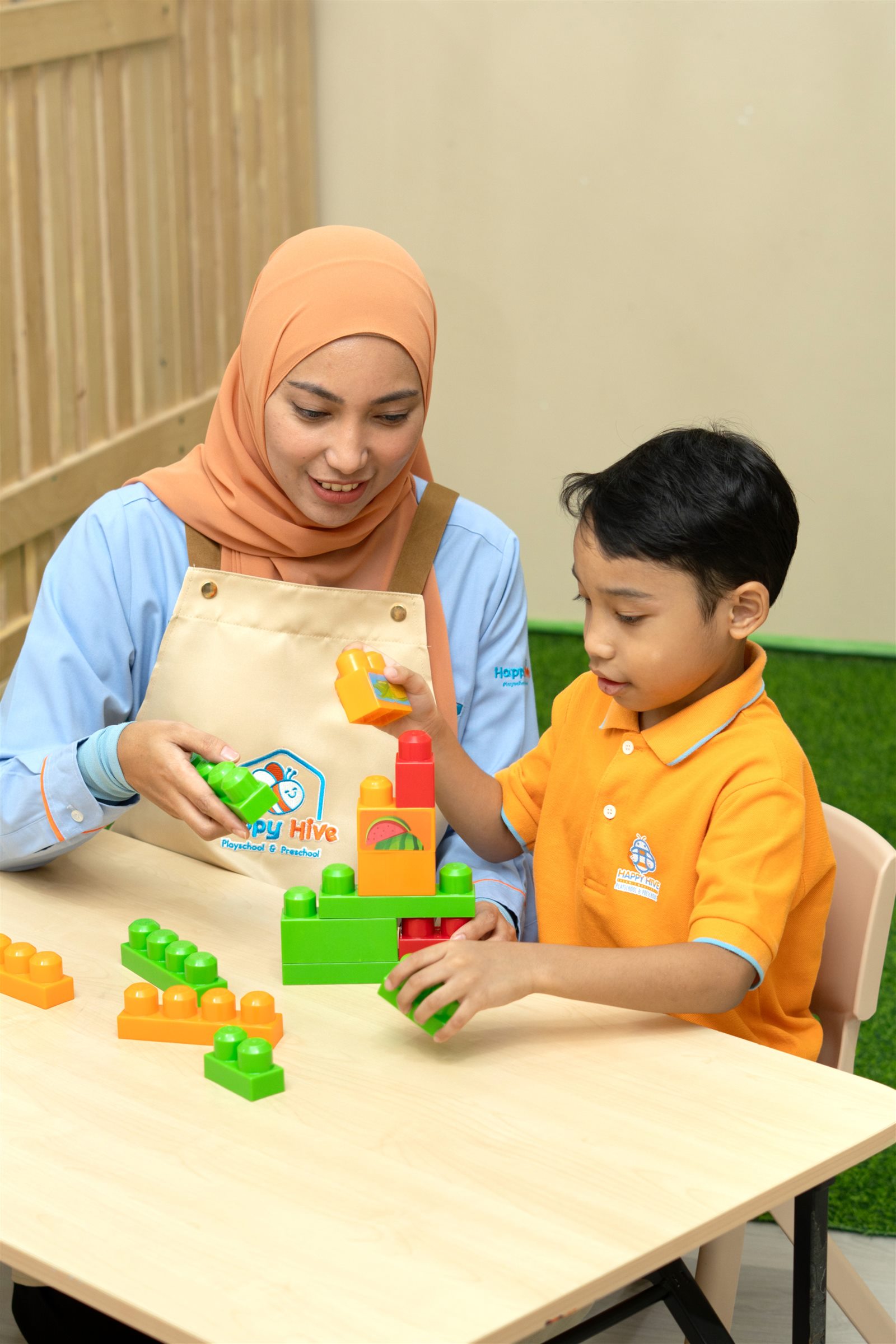 Happy Hive teacher guiding a child with colourful blocks